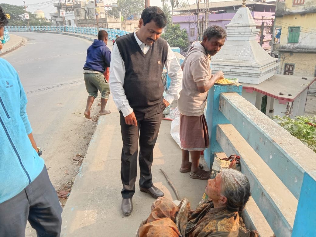 A volunteer speaking with an elderly woman seated on a bridge footpath