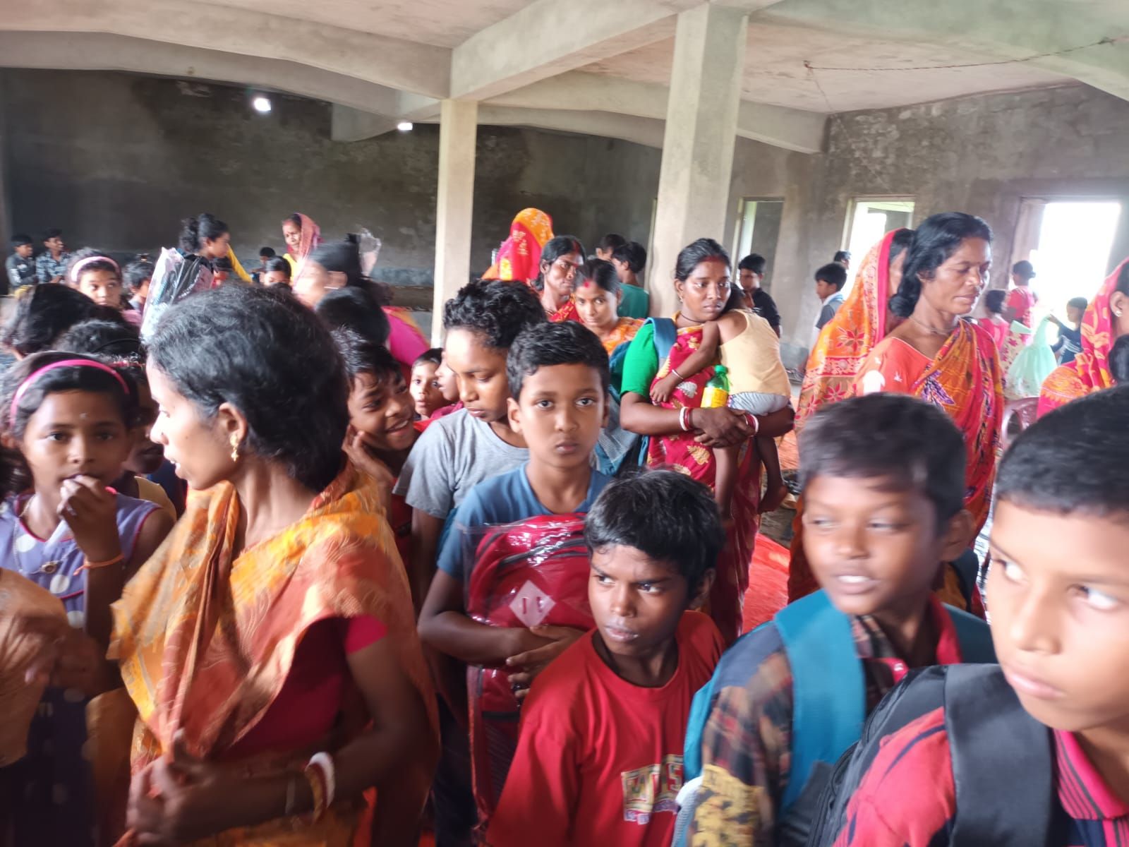 Families and children gathered in a hall waiting for a distribution