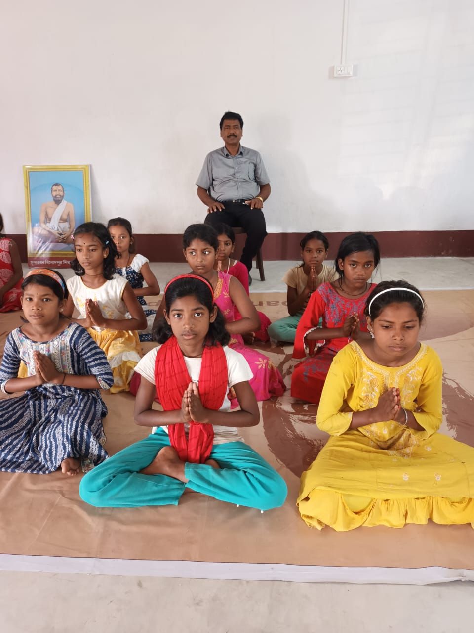 Girls sitting cross-legged with folded hands during a morning class
