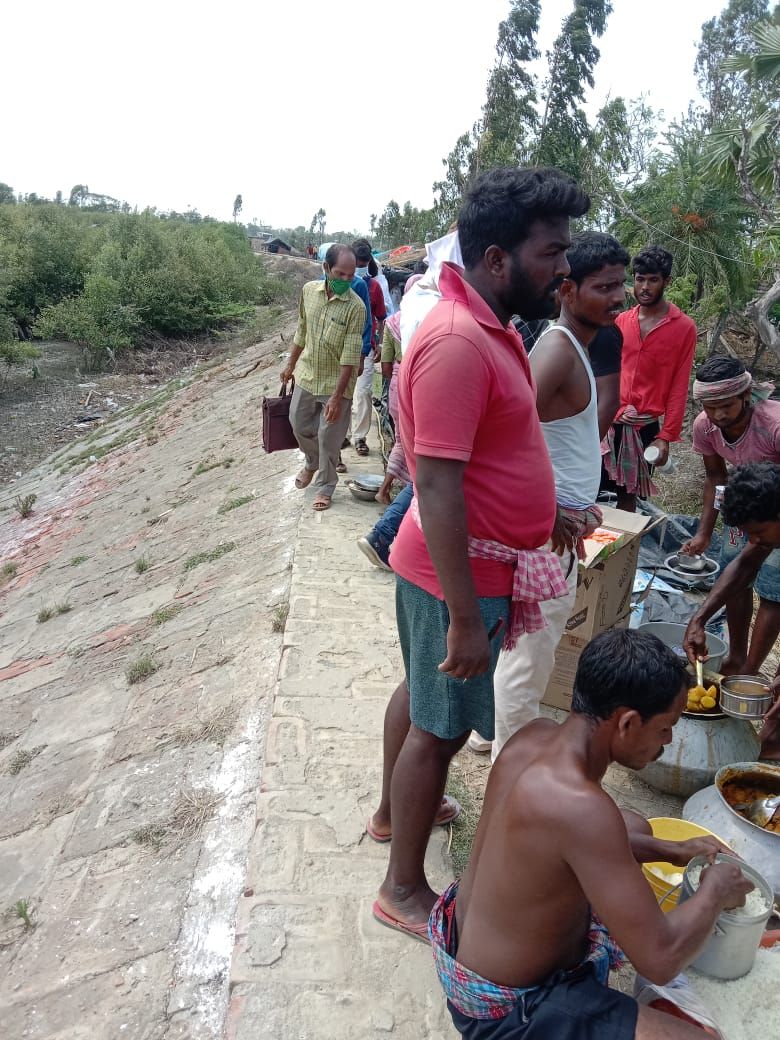 People lining up along an embankment for a community meal